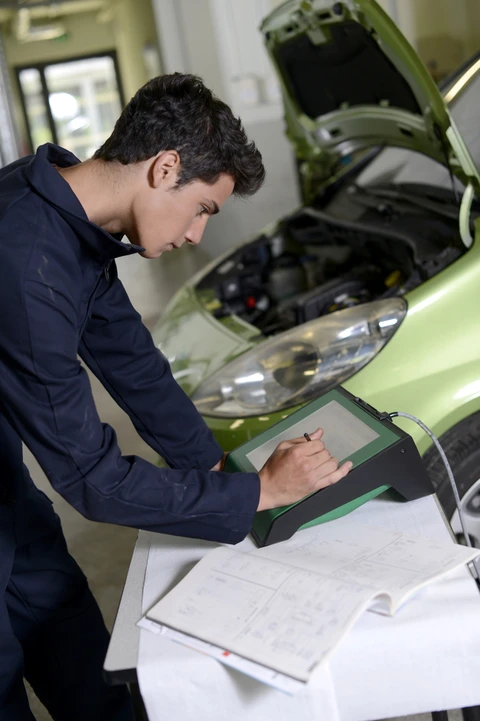 Scène d'atelier automobile high-tech montrant une berline BMW divisée par une ligne verticale orange
