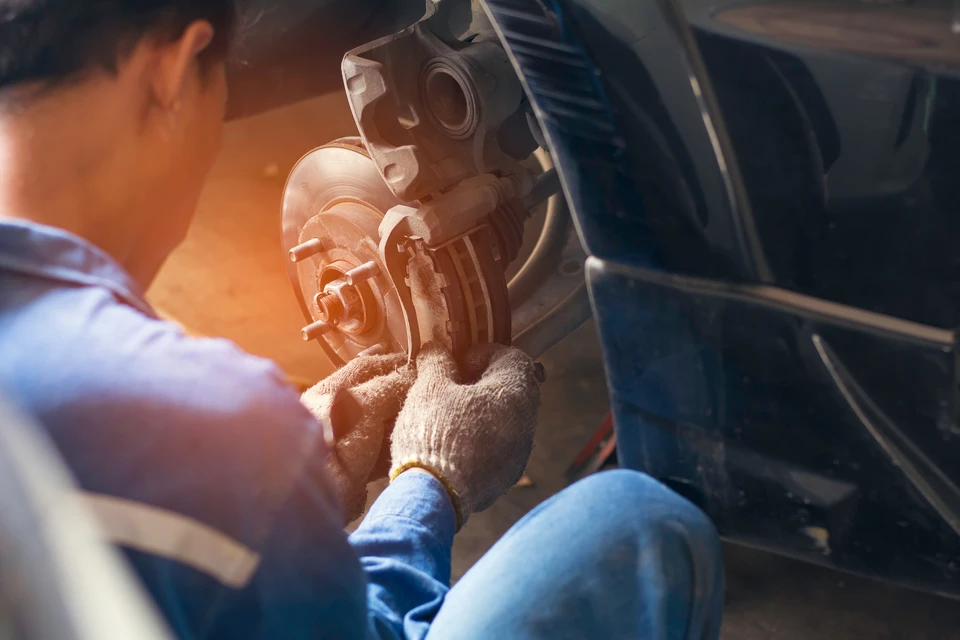 Mécanicien automobile travaillant sur système de freinage d'un véhicule en atelier