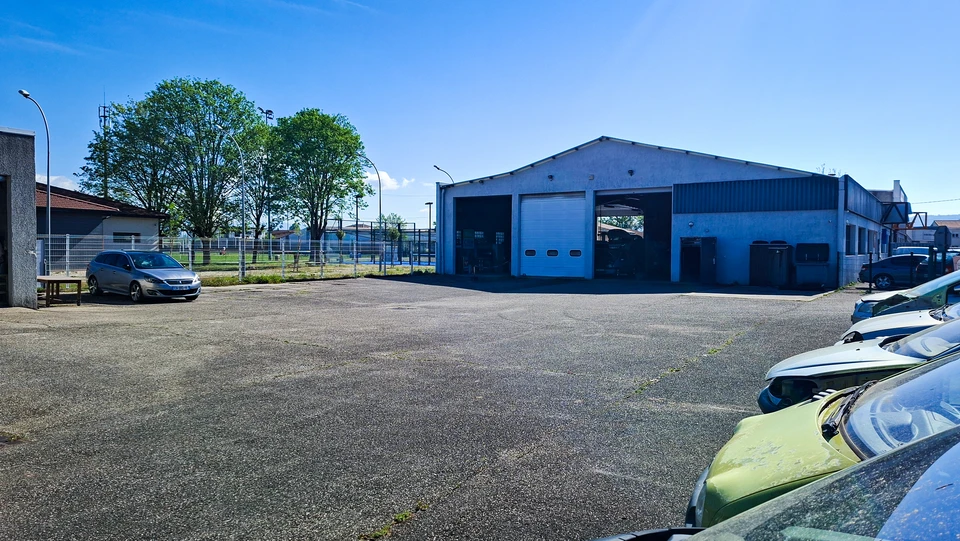 Mécanicien automobile en combinaison travaillant sous le capot ouvert d'un véhicule dans un garage professionnel