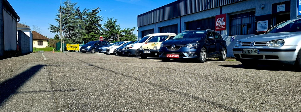 Mécanicien automobile en combinaison bleue effectuant maintenance moteur sur véhicule rouge dans garage professionnel