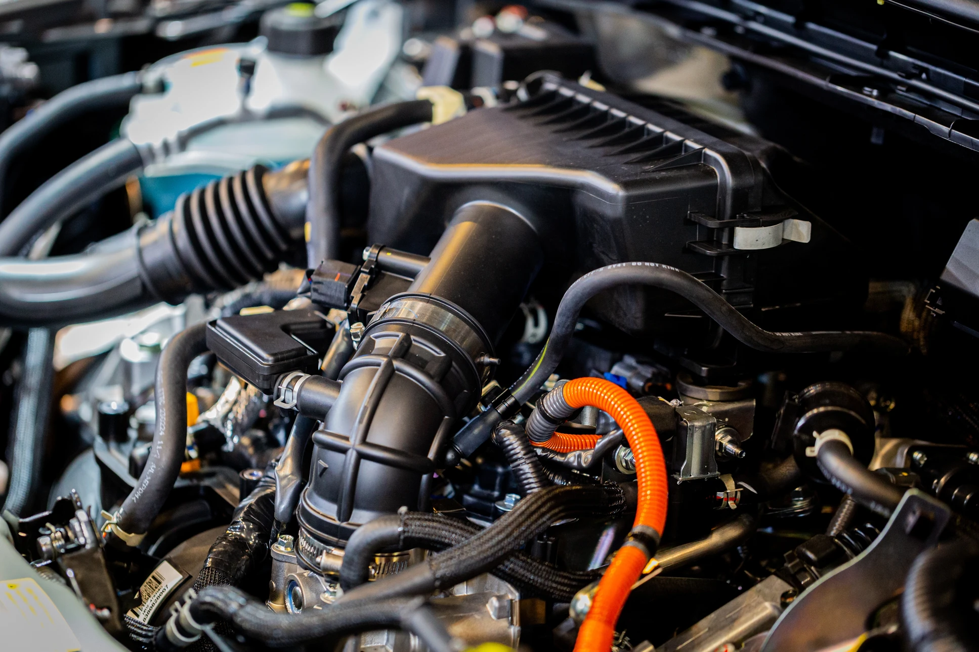 Mécanicien automobile en combinaison travaillant sous le capot ouvert d'un véhicule dans un garage professionnel