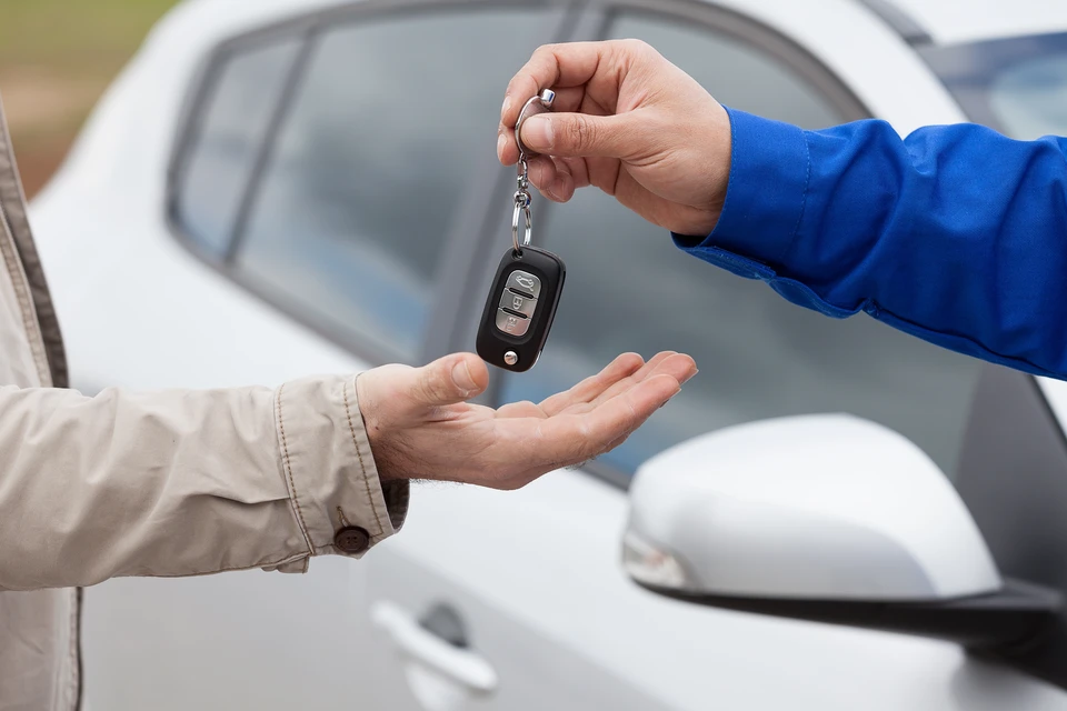 Scène intérieure d'un atelier automobile avec deux personnes échangeant des clés de véhicule