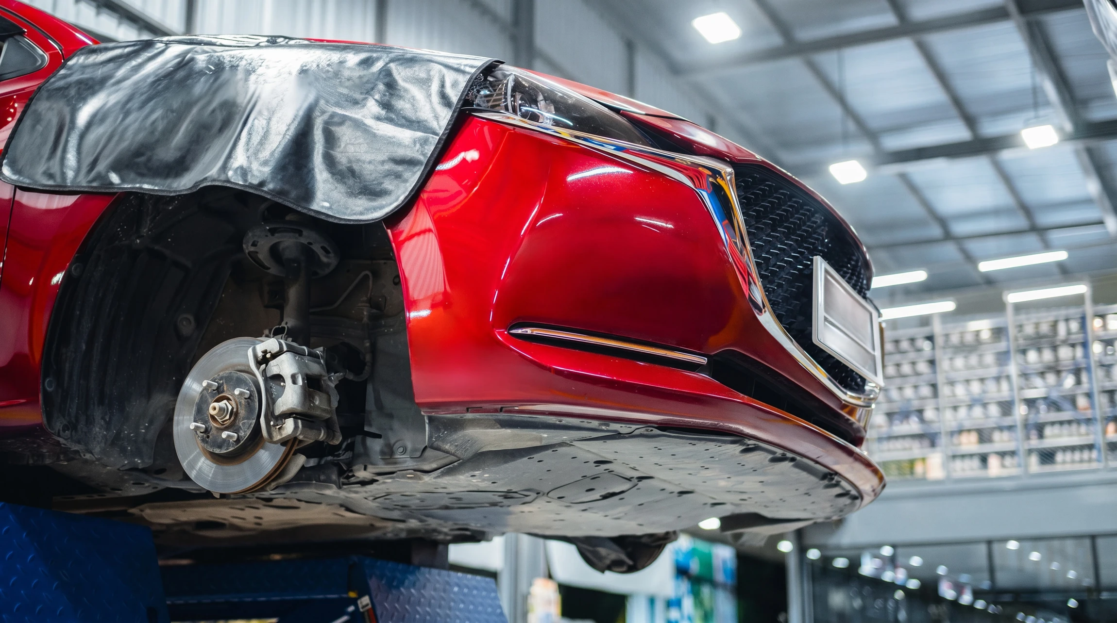Mécanicien automobile travaillant sous le capot d'un véhicule, utilisant un tournevis pour effectuer une réparation ou maintenance moteur
